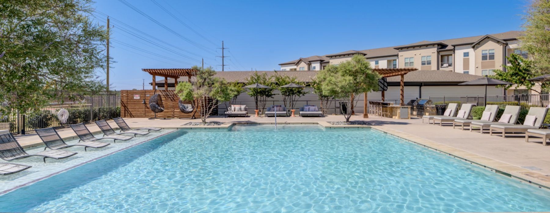 a swimming pool with chairs and a building in the background