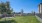 a grassy area with a fence and trees in the background