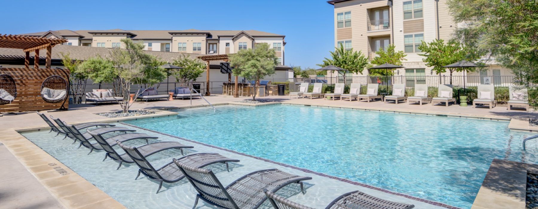 a pool with a lounge chair and a building in the background