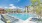 a pool with a lounge chair and a building in the background