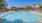 a swimming pool with chairs and a building in the background